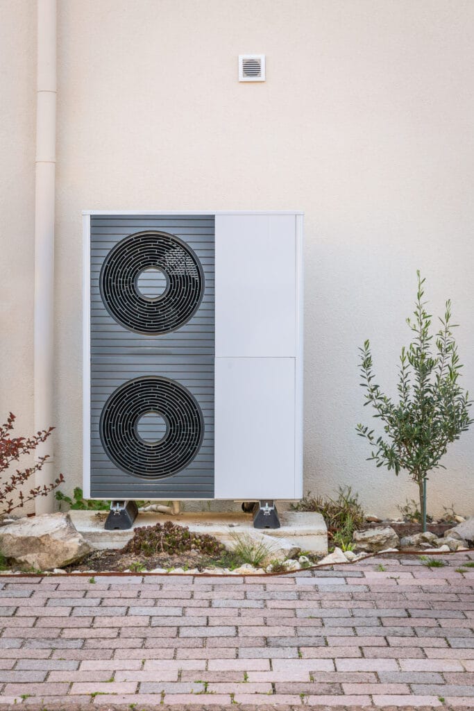Õhk-vesi soojuspumba välisosa kahe ventilaatoriga eramu seina ääres.